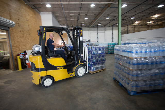 man using forklift to move pallets of water