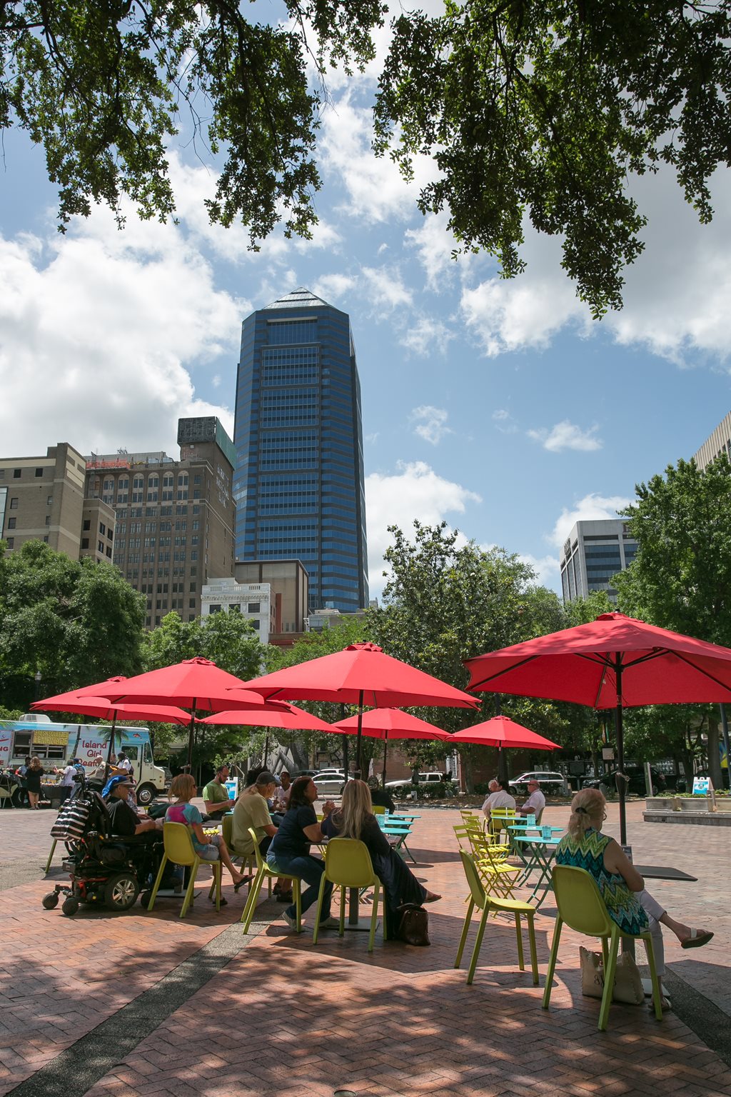 people sitting a umbrella covered tables in hemming park