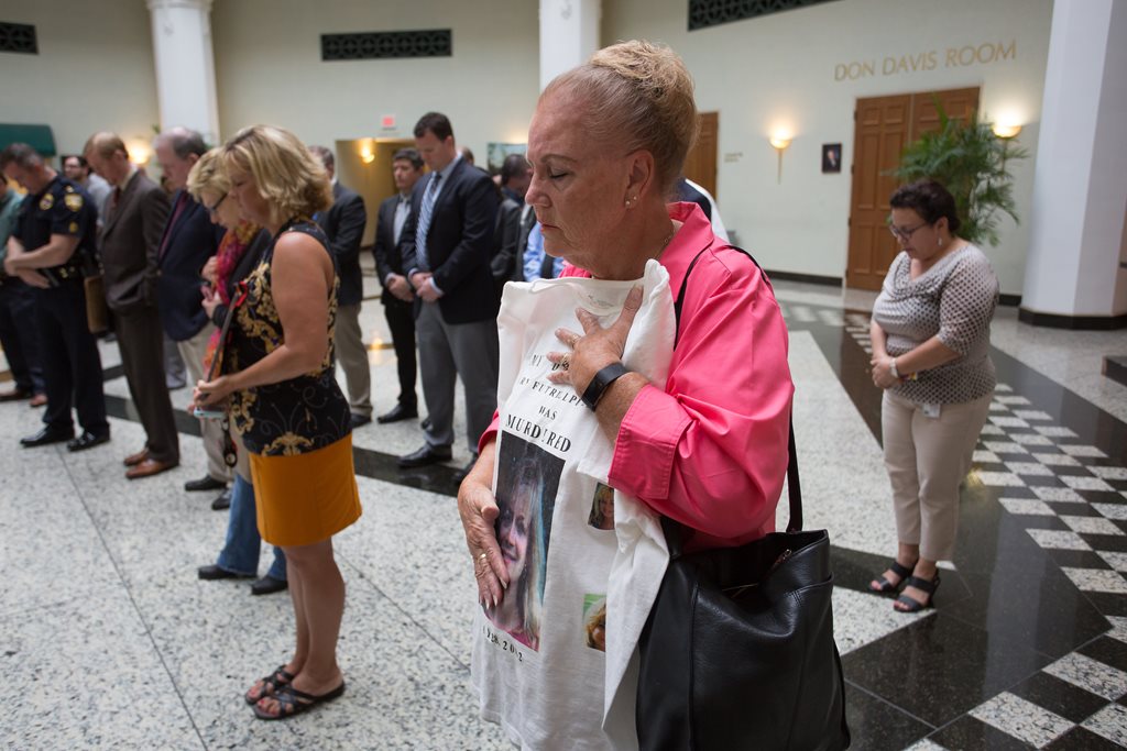 A family member of a victim  holds on to a t-shirt with a picture of her loved one during a prayer at the Victims Rights Week news conference on April 3, 2017.