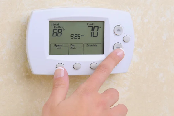 Person adjusting digital thermostat