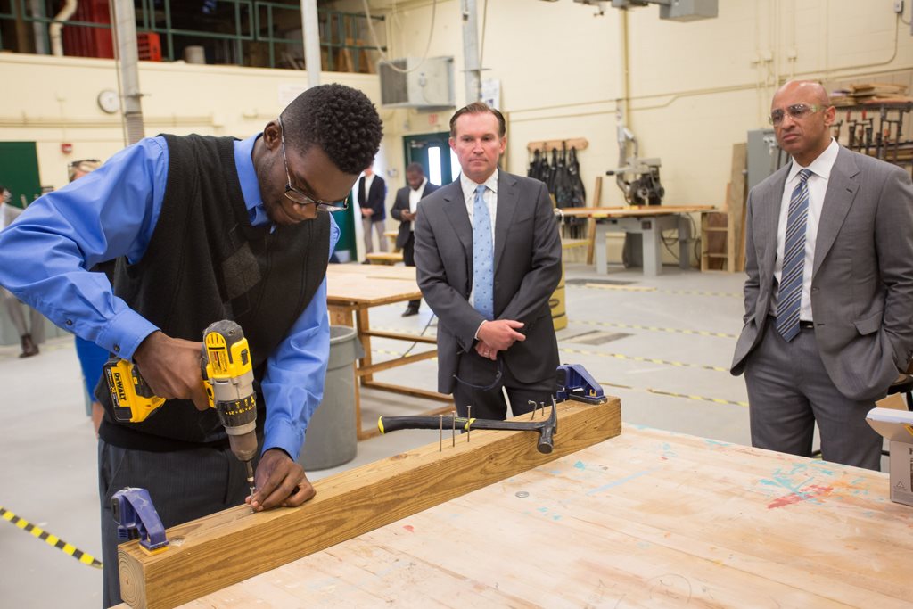 Mayor Lenny Curry and UAE Ambassador Yousef Al Otaiba observe a carpentry student a A. Philip Randolph Career Academies