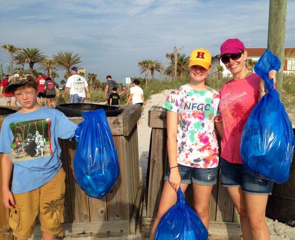 5th of July beach clean up volunteers holding bags of collected trash