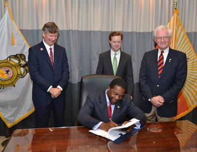 City Councilman Steven Joost, Council President Clay Yarborough and City Councilman Bill Gulliford watch as Mayor Alvin Brown signs the retirement reform bill into law