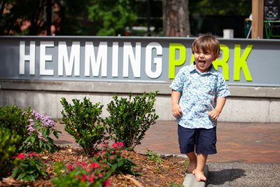 little boy walking in front of hemming park sign