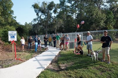 people and dogs standing at entrance to dog park