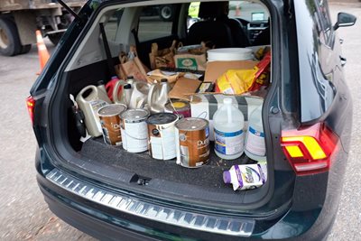 Trunk of car filled with paint can and hazardous household waste