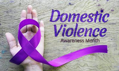 Hand holding purple ribbon for domestic violence awareness