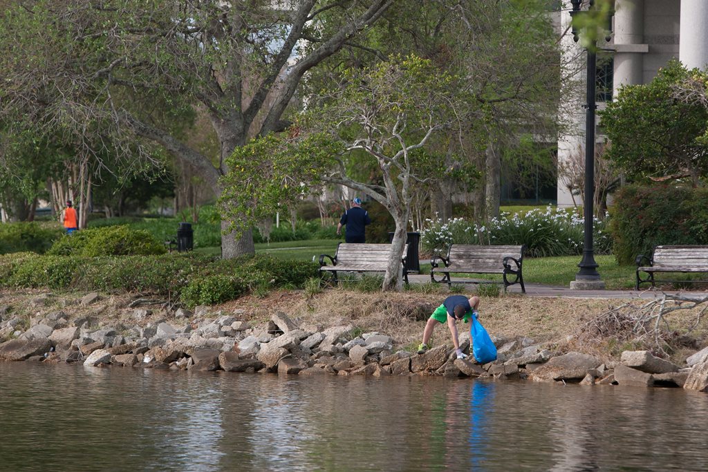 man cleaning trash along riverbank