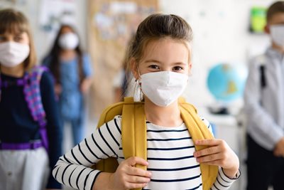 young girl wearing protective mask at school