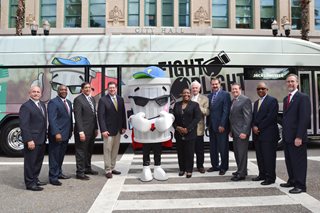 Photo of the members of the City Council Special Ad Hoc Committee on Neighborhood Blight and other city leaders with the Fight the Blight Mascot in front of a JTA bus that has been wrapped with Fight Blight information.